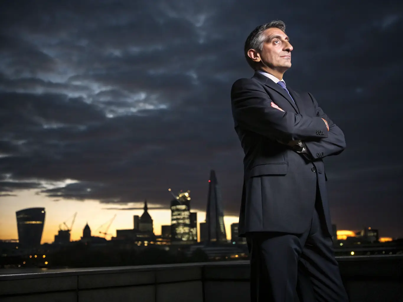A professional business coach in a suit, standing confidently in front of the London skyline, representing VanguardBrit's expertise in the UK market.